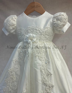 White lace dress with floral details on a hanger, branded 'Nene's Lullaby Boutique Inc NJ'.
