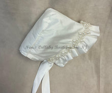 Load image into Gallery viewer, White baby bonnet with pearl embellishments on a beige background